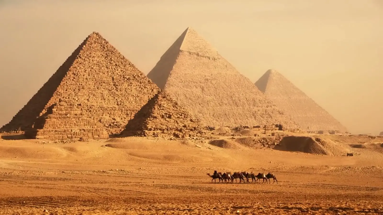 The Giza pyramids with a camel caravan crossing the desert